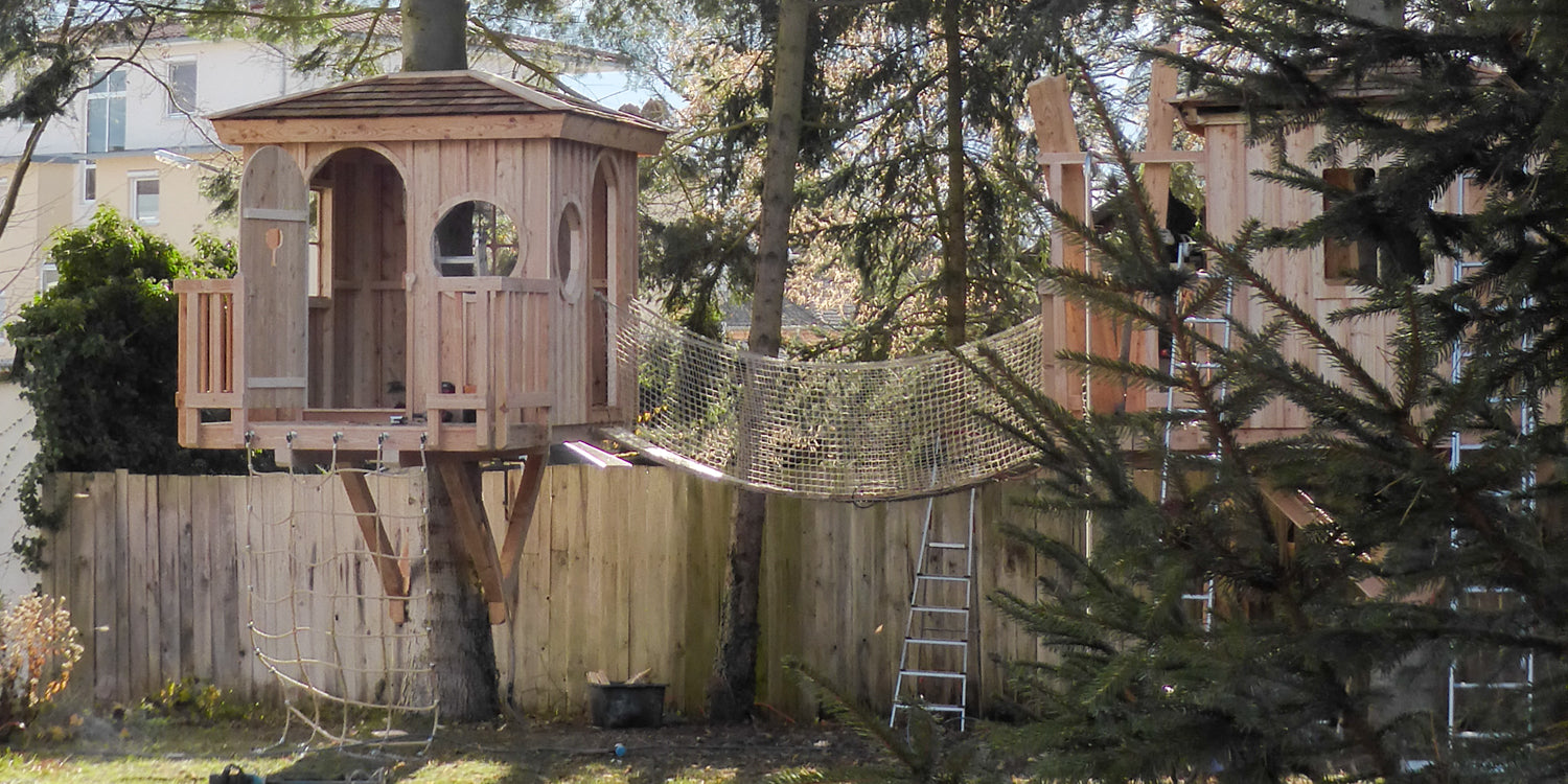 Small kids playhouse in trees with suspension bridge and climbing net