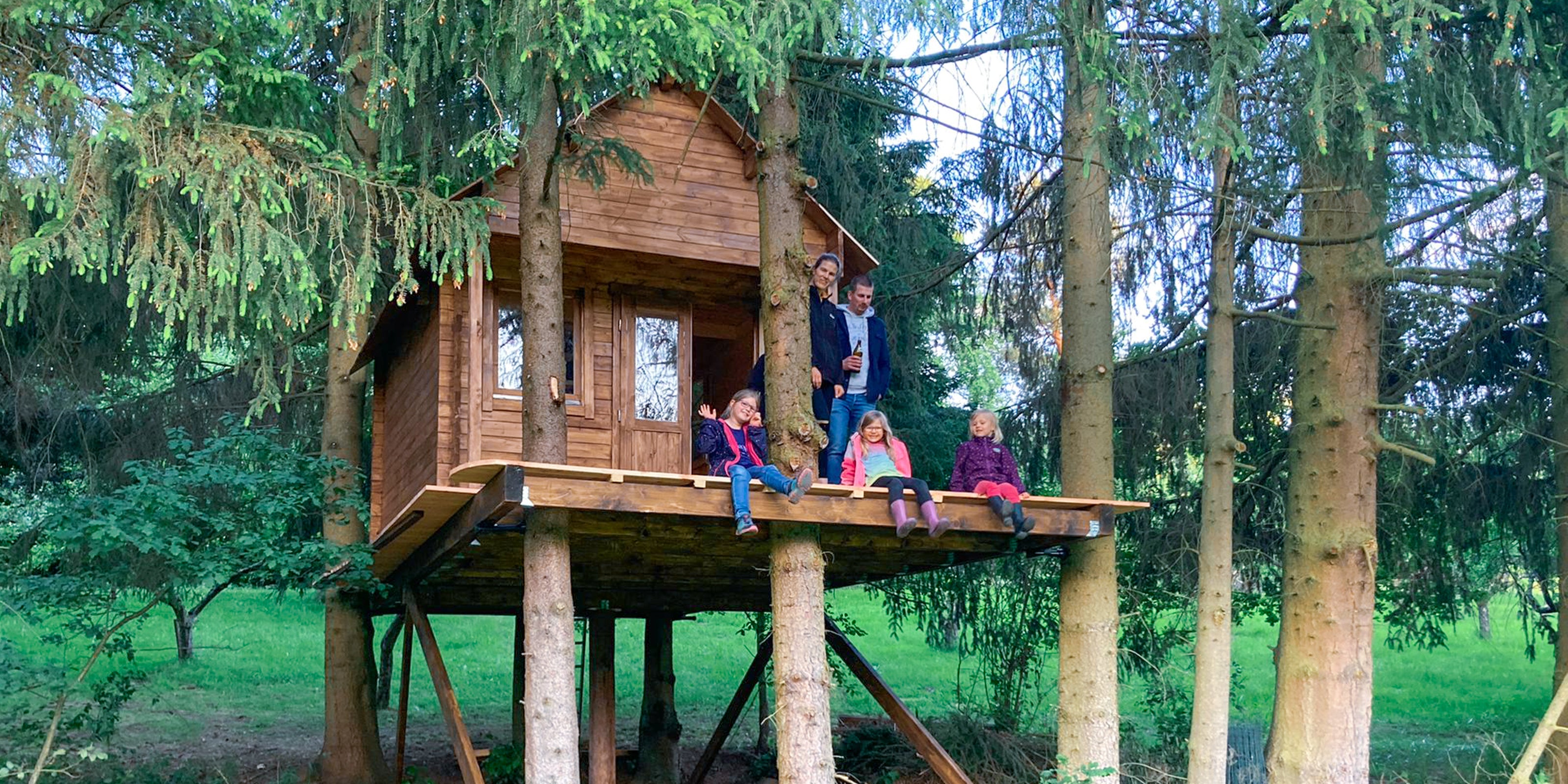 happy family with kids building diy treehouse in garden