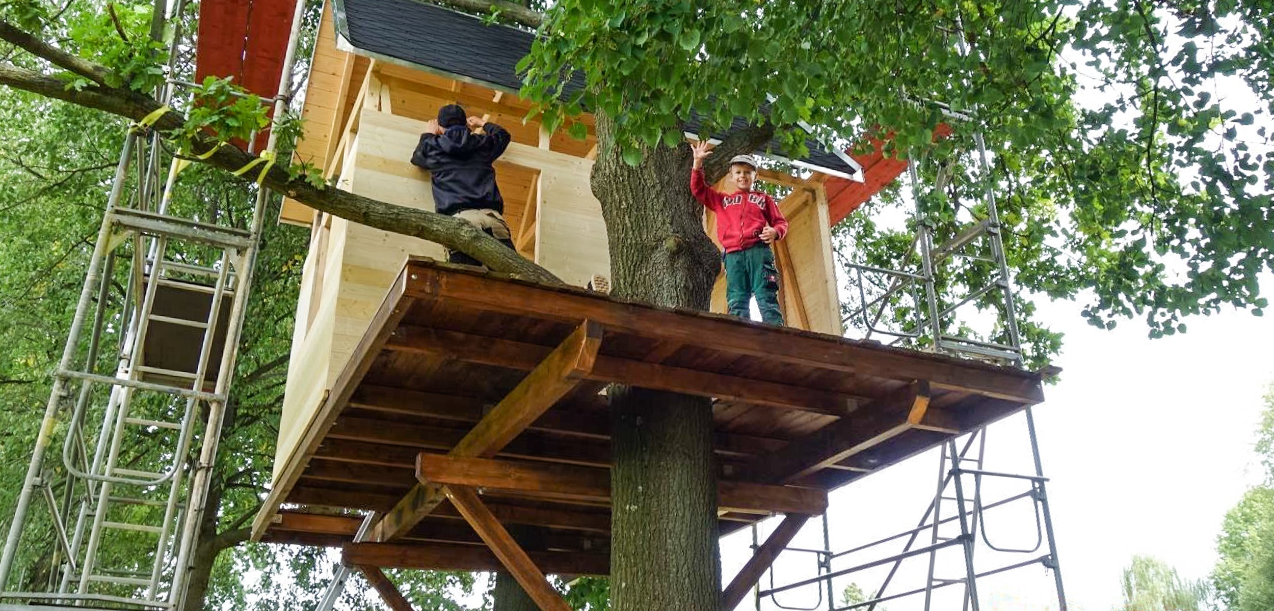 Baumhaus selbst bauen – DIY Bau Anleitung Mann baut an seinem Baumhaus glückliches Kind Baum in der Plattform Baugerüste