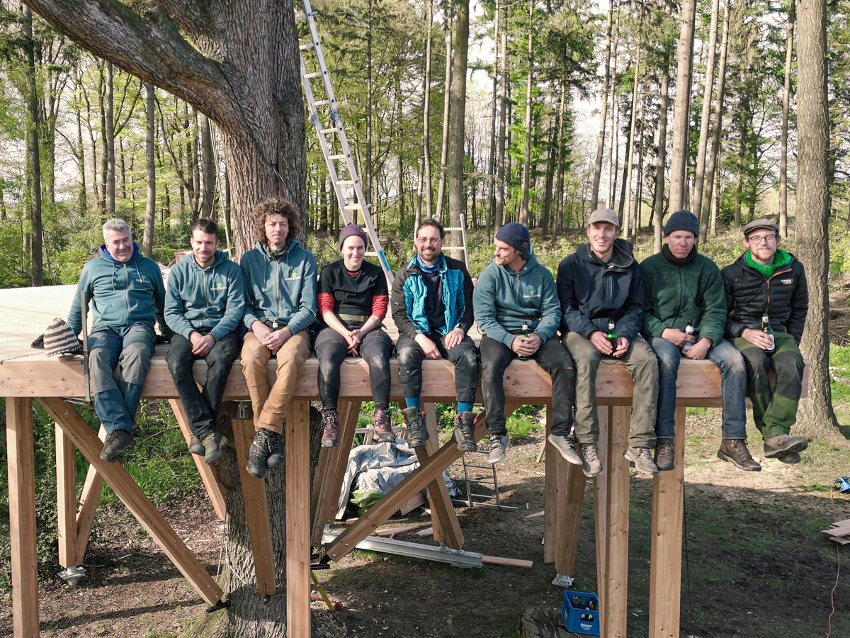 team of treehouse builders sitting on platform - baumbaron & thetreehouseshop